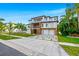 Three-story modern home boasts dual balconies, two-car garage, stylish driveway, and lush landscaping at 5964 Bayview S Cir, St Petersburg, FL 33707