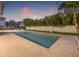 Backyard swimming pool features a modern design, travertine pavers, and privacy landscaping and fence at 5964 Bayview S Cir, St Petersburg, FL 33707
