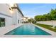 Tranquil swimming pool with a tiled patio, lush greenery, and view of the contemporary home at 5964 Bayview S Cir, St Petersburg, FL 33707