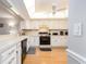 Well-lit kitchen with white cabinets, modern appliances, a ceiling fan, and wood-look floors at 640 Bayway Blvd # 302, Clearwater Beach, FL 33767
