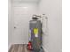 A utility room featuring a water heater and adjacent door, with durable flooring and easy access at 6612 W Chelsea St, Tampa, FL 33634