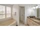 Well-lit primary bathroom featuring tiled floors, granite counters, soaking tub and shuttered window for privacy at 815 Sandy Trail Pl, Brandon, FL 33511