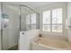 Light-filled primary bathroom with glass-enclosed shower and soaking tub with privacy shutters at 815 Sandy Trail Pl, Brandon, FL 33511