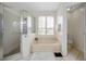 Bright primary bathroom featuring tiled floors, stand alone shower and soaking tub with shutters for privacy at 815 Sandy Trail Pl, Brandon, FL 33511