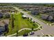 An aerial view of the community shows houses surrounding a large green park with walking paths and a covered structure at 8772 Flourish Dr, Land O Lakes, FL 34637