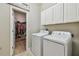 Laundry room with washer, dryer, overhead cabinets, and doorway to walk-in closet at 8772 Flourish Dr, Land O Lakes, FL 34637