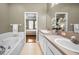 Bright bathroom featuring shower, soaking tub, and a double vanity with white cabinets at 10035 New Parke Rd, Tampa, FL 33626