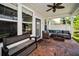 Well-appointed covered patio with brick flooring, cozy seating, a bench, and easy access to the outdoors at 10035 New Parke Rd, Tampa, FL 33626