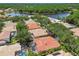 An aerial view of a residential area featuring mature trees, well-kept lawns, and homes with screened-in pools, near a scenic lake at 10229 Waterside Oaks Dr, Tampa, FL 33647