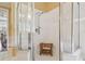 Modern glass enclosed shower featuring a wooden bench, white tile, and a handheld shower head fixture at 10229 Waterside Oaks Dr, Tampa, FL 33647