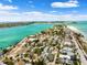 Beautiful aerial view showcasing beachfront homes, a sandy beach, and calm blue waters under a sunny, partly cloudy sky at 106 13Th Ave, St Pete Beach, FL 33706