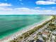 Vibrant aerial view featuring homes by a sandy beach and beautiful turquoise waters under a partly cloudy blue sky at 106 13Th Ave, St Pete Beach, FL 33706