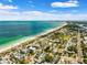 Stunning aerial view showcasing beachfront homes alongside a sandy beach and turquoise waters on a sunny, partly cloudy day at 106 13Th Ave, St Pete Beach, FL 33706