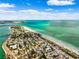 Breathtaking aerial view highlighting beachfront property, soft sandy beach, and inviting blue water on a partly cloudy day at 106 13Th Ave, St Pete Beach, FL 33706