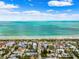Beautiful aerial view of beachfront homes, a sandy beach, and clear turquoise water under a sunny, partly cloudy sky at 106 13Th Ave, St Pete Beach, FL 33706