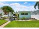 Charming light blue home featuring a well-kept lawn, patio, palm trees, and mature landscaping at 106 13Th Ave, St Pete Beach, FL 33706