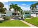 Charming home featuring a lovely deck with outdoor seating, lush lawn, and tropical landscaping at 106 13Th Ave, St Pete Beach, FL 33706