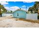 Back of home showcasing the light blue exterior with a gravel drive and partial fencing at 106 13Th Ave, St Pete Beach, FL 33706