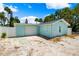 Rear of the home featuring a two car garage, light blue exterior, gravel, and a small fenced in area at 106 13Th Ave, St Pete Beach, FL 33706