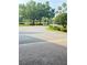 Entrance to community with asphalt drive bordered by green grass and mature trees at 1142 Sweet Jasmine Dr, Trinity, FL 34655