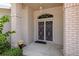 Close-up of the front door with decorative security doors and brick columns at 1142 Sweet Jasmine Dr, Trinity, FL 34655