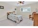 Bright bedroom featuring a bed with seashell themed bedding, ceiling fan, and shuttered window at 13533 Bay Lake Ln, Tampa, FL 33618