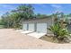 Three-car garage with white doors and blue trim against a backdrop of tropical landscaping at 13533 Bay Lake Ln, Tampa, FL 33618
