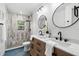 Bathroom featuring double sink vanity, round mirrors, modern fixtures, and wood-look tile on shower wall at 1400 23Rd S Ave, St Petersburg, FL 33705