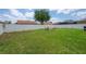 Expansive backyard with a white fence, lush green grass and a cozy fire pit seating area at 14614 Rannoch Moor Pl, Wimauma, FL 33598