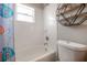 White-tiled bathroom showcasing a tub with a shower and colorful, playful fish shower curtain at 14614 Rannoch Moor Pl, Wimauma, FL 33598