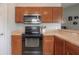 Kitchen with stainless steel microwave, black range, and warm wood cabinetry at 14614 Rannoch Moor Pl, Wimauma, FL 33598