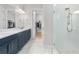 Bathroom with dual sink vanity, blue cabinets, and glass enclosed shower with marble tile at 15817 San Lazzaro Ave, Bradenton, FL 34211