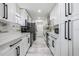 Modern galley kitchen with white cabinets, stainless steel appliances, and stylish backsplash at 1608 E Linden Ave, Tampa, FL 33604