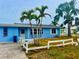 A blue home with palm trees and a white fence at 17595 1St E St, Redington Shores, FL 33708
