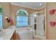 Bright bathroom with a soaking tub under an arched window and a separate glass-enclosed shower at 17711 Hampshire Oak Dr, Tampa, FL 33647