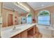 Large bathroom featuring double sinks, arched windows, a soaking tub, and a separate glass shower at 17711 Hampshire Oak Dr, Tampa, FL 33647