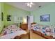Green-walled bedroom featuring two twin beds with wooden frames and laminate flooring at 17711 Hampshire Oak Dr, Tampa, FL 33647