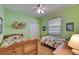 Twin bedroom with vibrant green walls, ceiling fan, and two matching wooden beds at 17711 Hampshire Oak Dr, Tampa, FL 33647