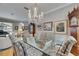 Formal dining room with glass table set and chandelier adjoins a living area with a piano at 17711 Hampshire Oak Dr, Tampa, FL 33647