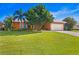 Well-maintained house featuring an orange facade, lush green lawn, a two car garage, and mature trees at 1960 Montana Ne Ave, St Petersburg, FL 33703