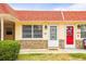 Charming condo featuring a decorative stone facade, bright red roof, and well-manicured landscaping at 230 Portree Dr, Dunedin, FL 34698