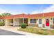 Charming condo featuring a red roof, well-manicured landscaping, and convenient carport at 230 Portree Dr, Dunedin, FL 34698