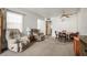 Comfortable living room with two recliners and a dining area featuring a ceiling fan and neutral carpet at 230 Portree Dr, Dunedin, FL 34698
