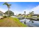 Scenic pond view with palm trees, a white foot bridge, and lush landscaping surrounding inviting homes at 230 Portree Dr, Dunedin, FL 34698