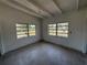 Bedroom with exposed beam ceiling, two windows and view of lush greenery outside at 3000 58Th S Ave, St Petersburg, FL 33712