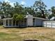 Exterior of the home featuring a screened porch, brick accents, and landscaping against a backdrop of mature trees at 3000 58Th S Ave, St Petersburg, FL 33712