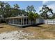Exterior of the home featuring a screened porch, brick accents, mature landscaping, and a white fence at 3000 58Th S Ave, St Petersburg, FL 33712