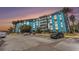 Bright blue condo building with ample parking and lush palm trees, offering a vibrant living space at 3315 58Th S Ave # 605, St Petersburg, FL 33712