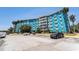 Bright blue condo building with ample parking and lush palm trees, offering a vibrant living space at 3315 58Th S Ave # 605, St Petersburg, FL 33712