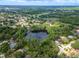 High aerial view showcasing a community with mature trees surrounding a neighborhood with a lake in the center at 3428 Valley Ranch Dr, Lutz, FL 33548